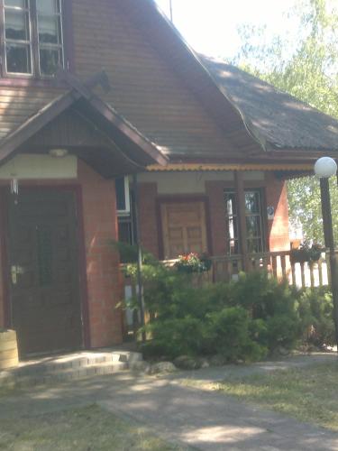 a red brick house with a porch and a door at Kempings Mežmalas in Usma