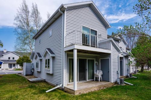 a white house with a porch and a lawn at Holiday by the Bay Unit A-4 by Simple Life Rentals in Fish Creek
