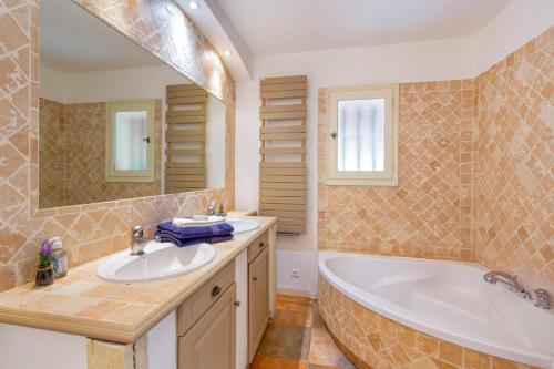 een badkamer met 2 wastafels, een bad en een spiegel bij Villa Beauregard by Villa Plus in Tourrettes