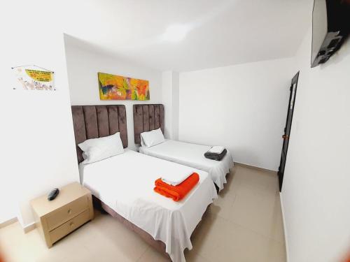 two beds in a small room with an orange pillow at Karin Hotel in Ríohacha