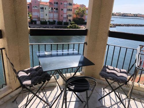 Una mesa y sillas en un balcón con vista al agua. en Studio chaleureux avec piscine, en Le Barcarès