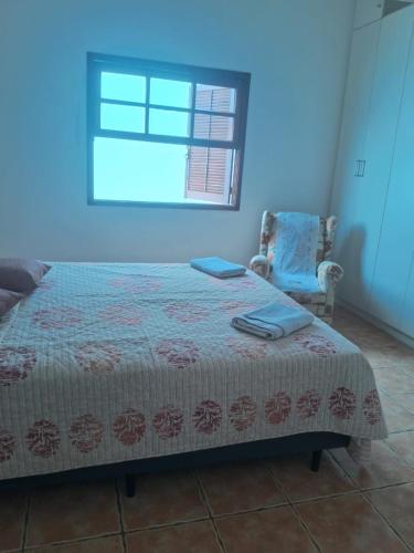 a bedroom with a bed and a chair and a window at Casa Rua Salvia, Jd Tulipa in Holambra