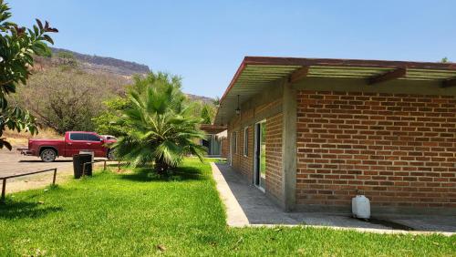 a brick building with a palm tree in front of it at Rancho El Venado Termales in Acatic