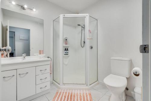 a white bathroom with a shower and a toilet at Golden Retreat, Central Mount Maunganui in Mount Maunganui