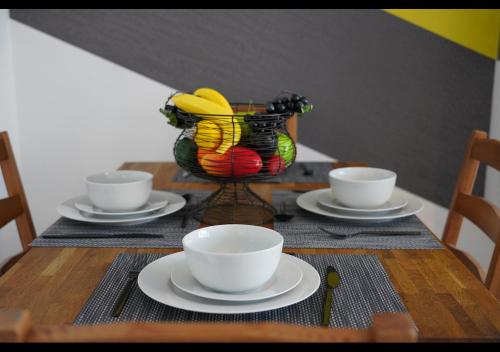 a table with plates and cups and a basket of bananas at Cosy 2 bedroom on Bromley-Lewisham Hospital Borders in Catford