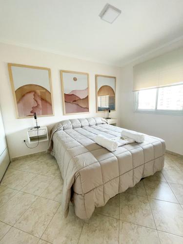 1 cama grande en un dormitorio blanco con cuadros en la pared en Saavedra 118 2°J by depptö, en Bahía Blanca