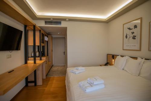 a hotel room with a bed with towels on it at Agnanti Limnis Hotel in Neochori