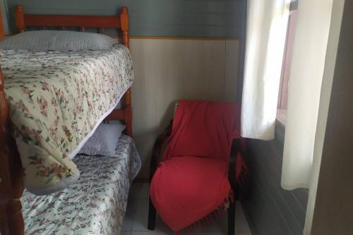 a bedroom with a bed and a red chair at Res Canto dos Pássaros - Chalé 03 in Rio Grande