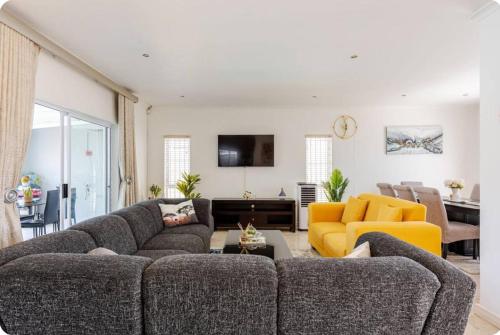 una sala de estar con 2 sofás y una silla amarilla en JDBA Homes of Luxury, en Ciudad del Cabo