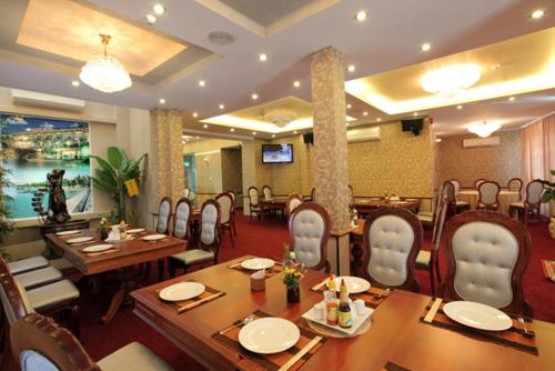 a restaurant with wooden tables and chairs and a television at Grand Hotel Vung Tau in Vung Tau