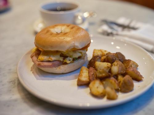 a sandwich and potatoes on a plate with a cup of coffee at Hotel Julian in San Francisco