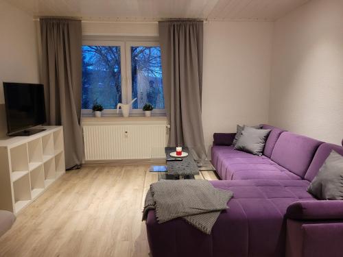 Una sala de estar con un sofá morado y un televisor. en Ferienwohnung mit Balkon, en Holle