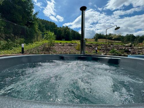 a hot tub filled with water in a field at Chata pod Cigerníkom in Matiašovce