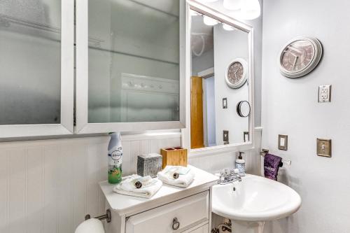 Un baño blanco con lavabo y espejo. en Near Hiking Cozy Anchorage Retreat with Fireplace!, en Anchorage