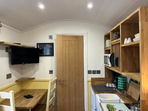 a room with a kitchen with a table and a door at The Shepherd's Nook in Thirlmere