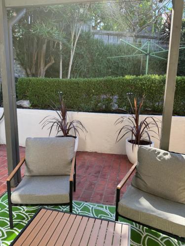 two chairs and a table on a patio with plants at 3 Bedroom Beach House in Coogee in Sydney