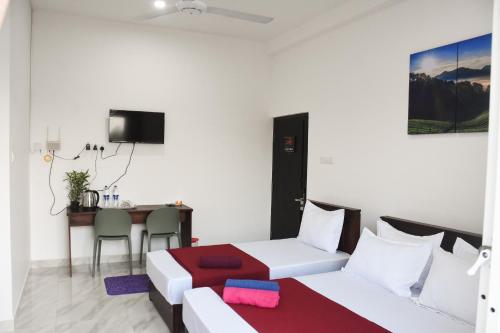 Habitación con cama, mesa y escritorio. en Solid Hotel Boralasgamuwa, en Boralesgamuwa
