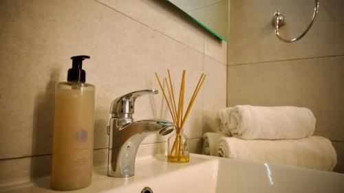 a bathroom sink with a bottle of soap next to a faucet at Sea Front Studio with Valletta Views in Kalkara