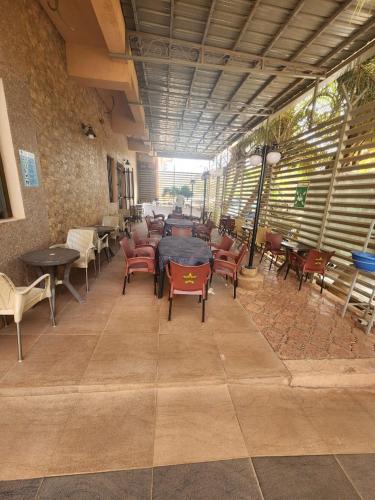 a dining room with tables and chairs and a table at Hotel Les Fleurettes in Ouagadougou
