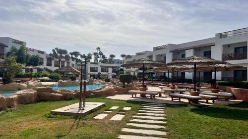 a resort with benches and umbrellas and a pool at Domina Coral Bay Elisir in Sharm El Sheikh