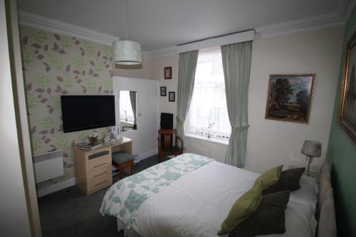 a bedroom with a bed and a flat screen tv at Bluestones in Keswick