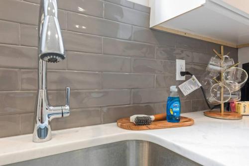 a kitchen sink with a faucet and a bottle of cleaner at Teche House KING Bed Luxury Getaway Fast WiFi in Lafayette