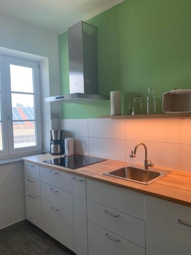 a kitchen with white cabinets and a sink and a window at FeWo Frido in Fridolfing