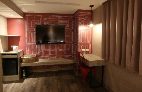 a room with a red wall with a flat screen tv at Central Hotel in Zhongli