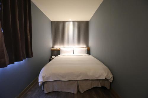 a bedroom with a white bed with a window at Central Hotel in Zhongli