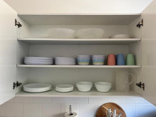 a kitchen cabinet filled with plates and bowls at 3 Bedroom Beach House in Coogee in Sydney