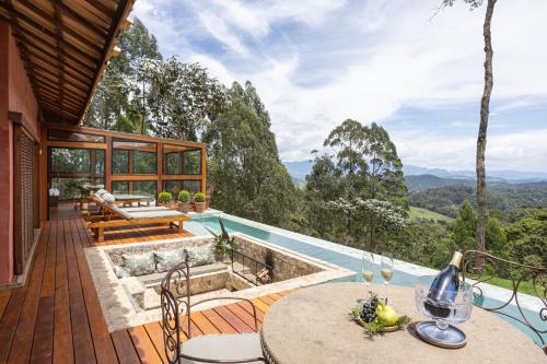 a house with a plunge pool and a deck with a table and chairs at Quinta dos Pinhais Pouso e Charme in Santo Antônio do Pinhal