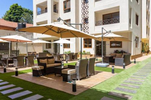 a patio with tables and chairs and umbrellas at Nairobi City view1 BDRM condo with pool and gym in Nairobi
