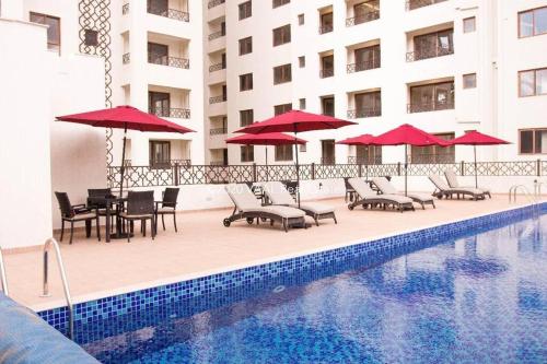 a pool with chairs and umbrellas next to a building at Nairobi City view1 BDRM condo with pool and gym in Nairobi
