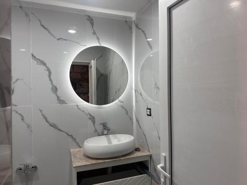 a white bathroom with a sink and a mirror at Rova Hotel in Baku
