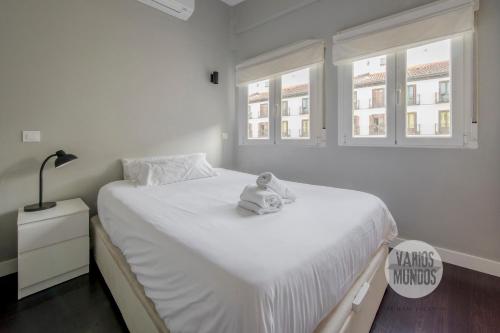 a white bedroom with a teddy bear sitting on a bed at Sutil elegancia para 3, en Plaza de Chueca in Madrid