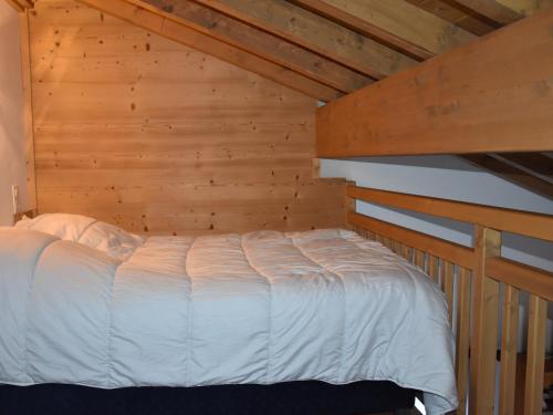 un lit dans une chambre avec un mur en bois dans l'établissement Studio confortable à Pralognan, proche patinoire et téléphérique - FR-1-464-192, à Pralognan-la-Vanoise