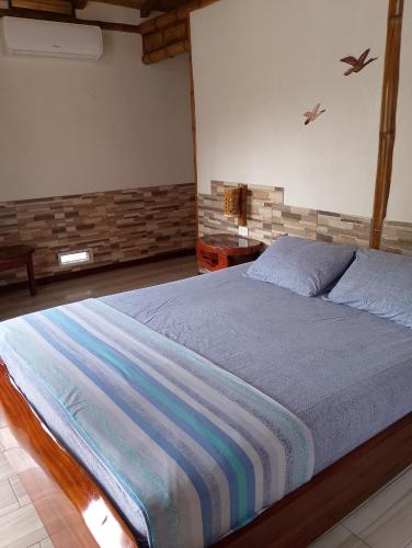 a bedroom with a bed with a blue comforter at Cabañas Riviera Pacific in Pedernales