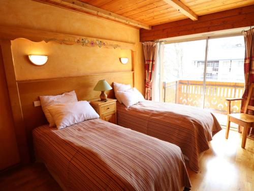 two beds in a room with a window at Appartement cosy près du centre et des pistes avec balcon, parking, 6 couchages - FR-1-623-305 in Les Gets