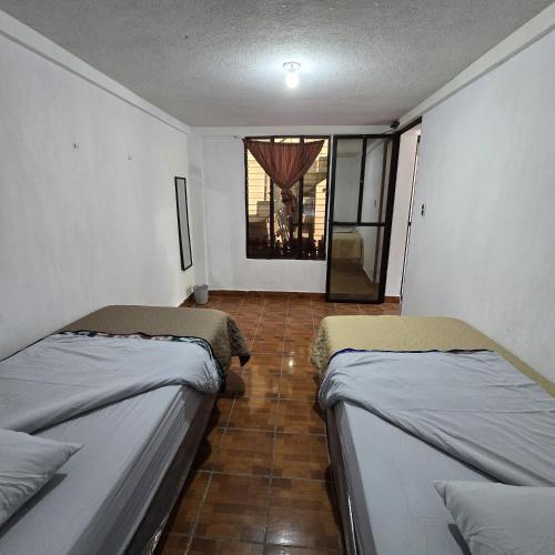 two beds in a small room with a window at Apartamentos el viajero in Panajachel