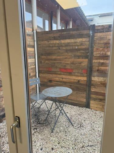 a table and a chair in front of a fence at Appartement avec extérieur in Muret