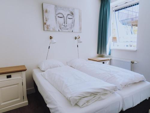 a bed with white sheets on it in a room at Spacious Lakeside Retreat in Uitgeest