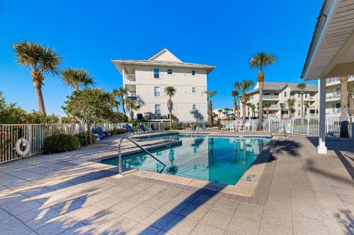 a swimming pool in front of a building with palm trees at Gulf Island 733 in Navarre