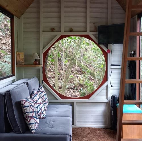a living room with a couch and a round window at Tiny House da serra perto de São Paulo em meio a natureza in Mairiporã