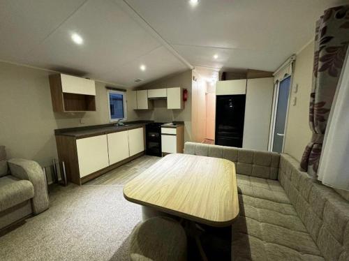 a kitchen and living room with a table and a couch at Willerby, Peppy, Sycamore Walk, Lyons Robin Hood Holiday Park in Rhyl