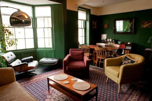 a living room with green walls and a table and chairs at The Writer's House in Canterbury