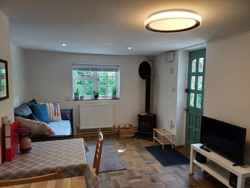 a living room with a couch and a television at Offa's Hideaway - Wye Valley in Newland