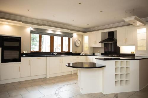 a large kitchen with white cabinets and black counter tops at Tara Manor - Family gathering's & hen parties in Omagh