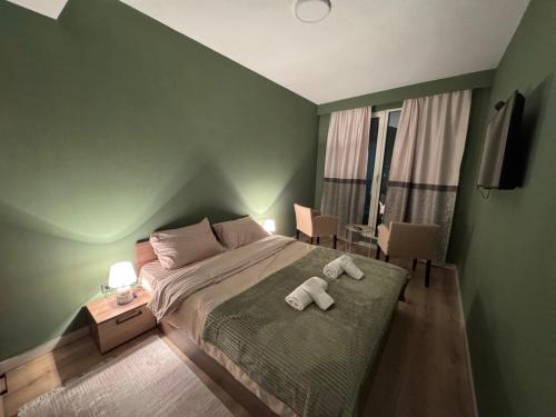 a green bedroom with a bed with two towels on it at Sky Lux Point in Skopje