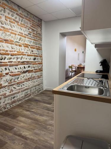 a kitchen with a brick wall and a sink at Logement T3 centre-ville in Muret