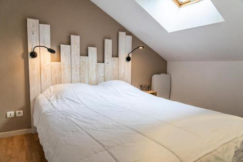 une chambre avec un lit blanc avec une tête de lit en bois dans l'établissement Résidence La Combe D'or - Confortable et moderne appartement 4 personnes MAE-3751, aux Orres
